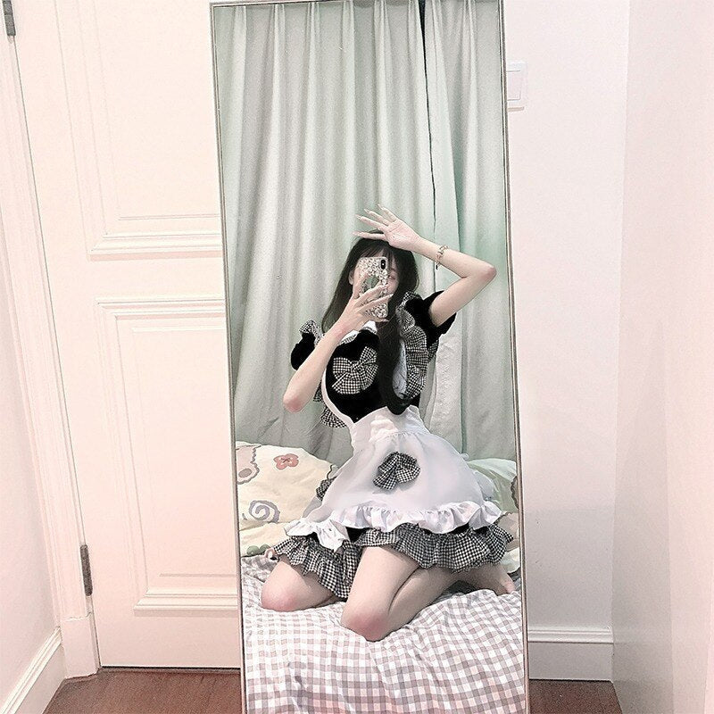 French maid cosplay: person kneeling on bed, taking a mirror selfie in sassy maid costume