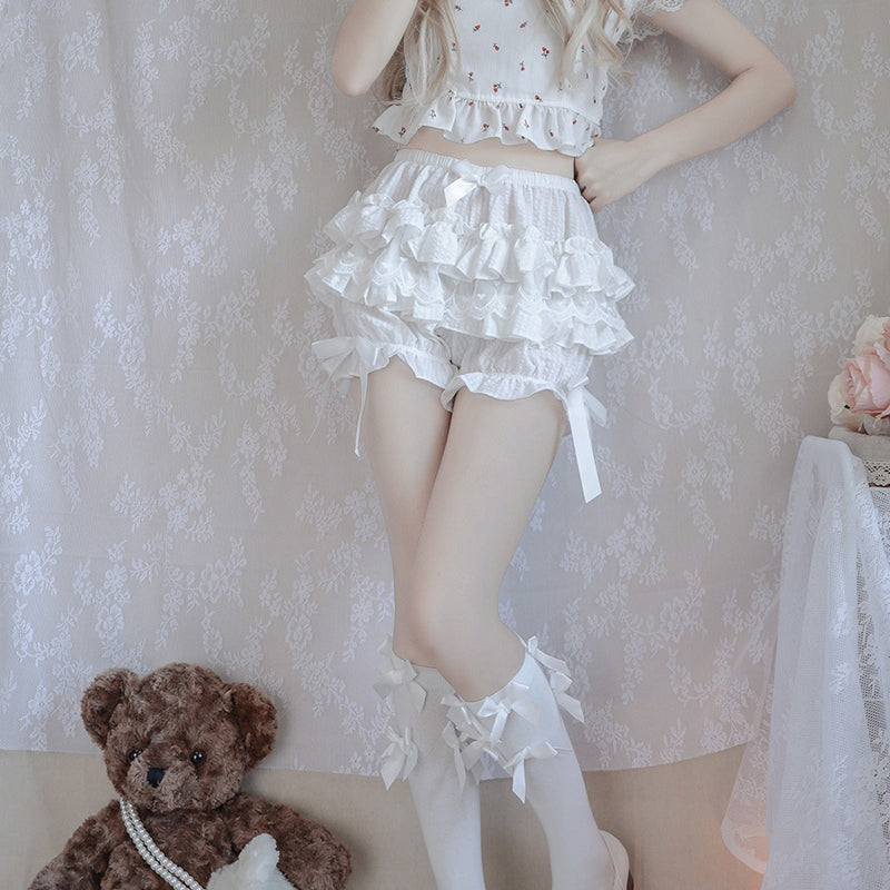 Frilly white two-piece outfit with ruffled crop top and layered skirt worn with knee-high socks.