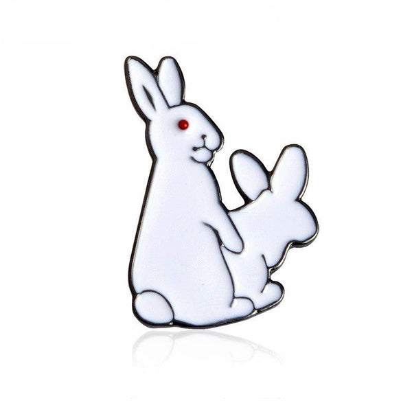 White rabbit-shaped pin or brooch with a red eye and a smaller rabbit silhouette behind it.