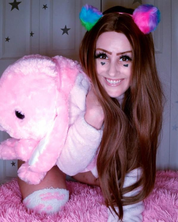 Woman with long brown hair wearing colorful cat ears and holding a pink plush toy.